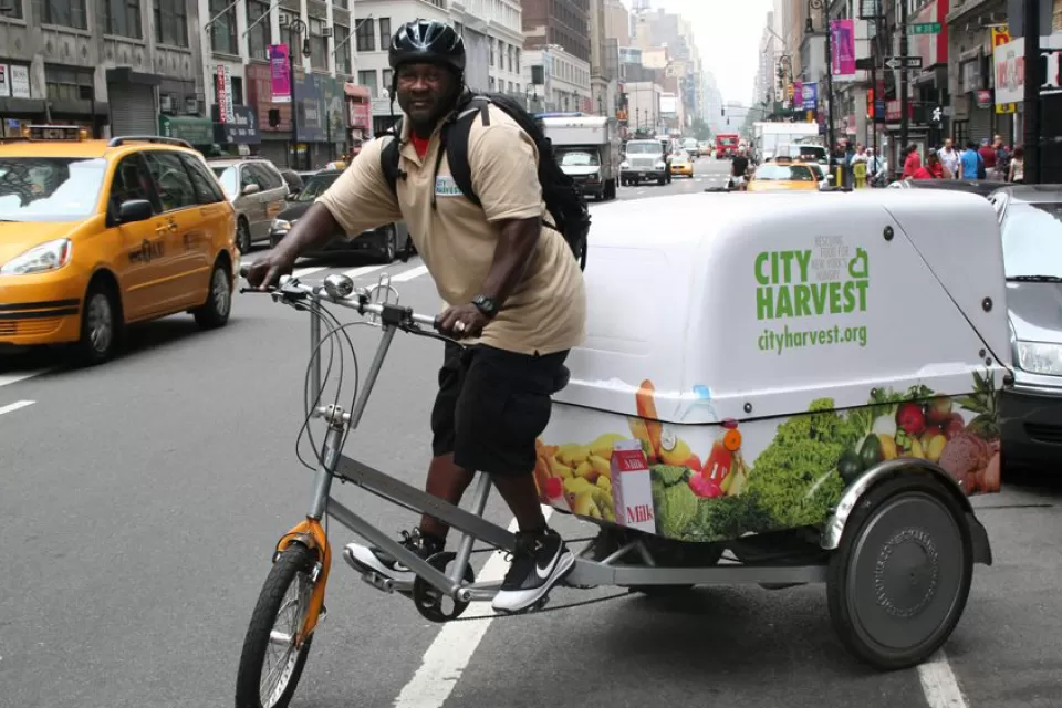 Man riding bike in New York with City Harvest cargo compartment attached